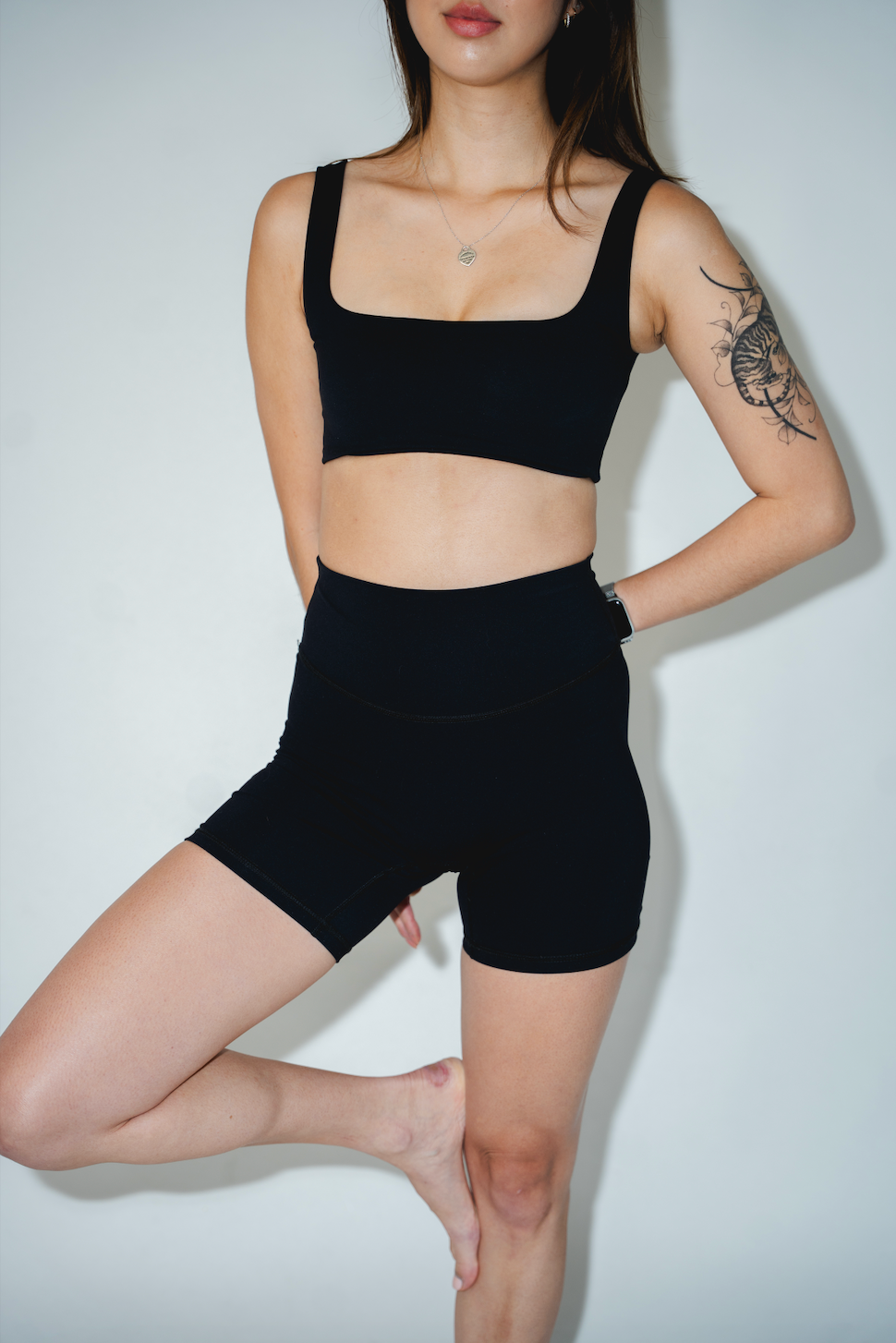 Person wearing a black sports bra and shorts on a white background